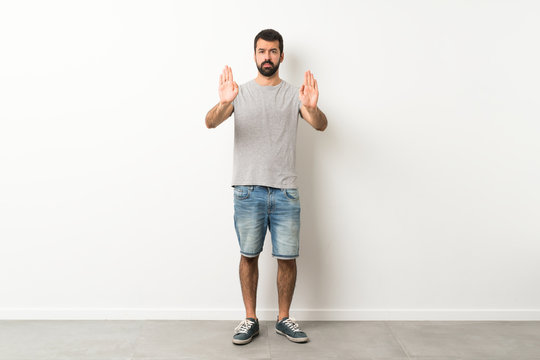 A full-length shot of handsome man with beard making stop gesture and disappointed