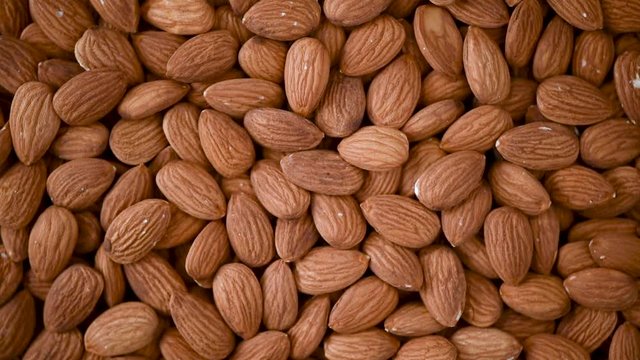 Almond nuts close up. Food ingredient background. Vegan, vegetarian diet. Healthy lifestyle. Natural dry fruits and nuts concept product. Almond kernels rotating