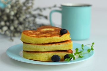 American pancakes on blue plate for healthy breakfast on white table with spring flowers.Breakfast on Valentine's Day or 8 March - pancakes in the shape of a heart.Pancake week.