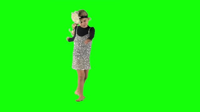 Female child with blond hair turning around and dancing on green background