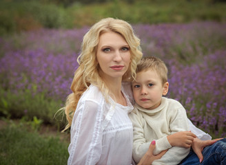  happy mom with a boy have a rest in a lavender field in summer