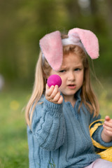 Girl with bunny ears collects chocolate eggs for Easter