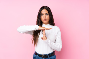 Young woman over isolated pink background making time out gesture