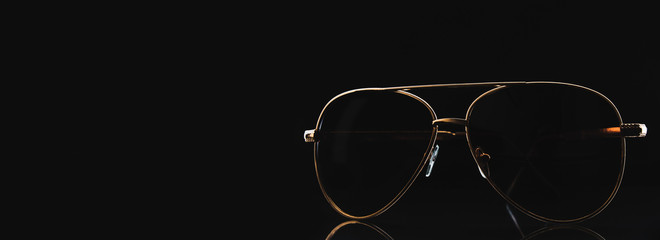 Gold-rimmed sunglasses on a dark background. Space for text or design