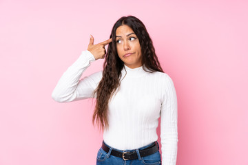 Young woman over isolated pink background making the gesture of madness putting finger on the head