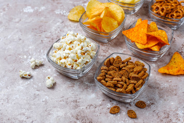 Salty snacks. Pretzels, chips, crackers,popcorn in bowls. Unhealthy products. food bad for figure, skin, heart and teeth. Assortment of fast carbohydrates food