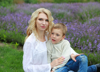Fototapeta na wymiar happy mother with boy holding hands have a rest in lavender field in summer