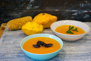 Pumpkin soup in a bowl on a blue and white wooden background. From above