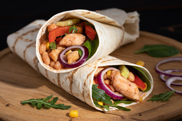 Burritos wraps with chicken and vegetables on dark background. Mexican food