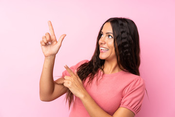 Young woman over isolated pink background pointing with the index finger a great idea