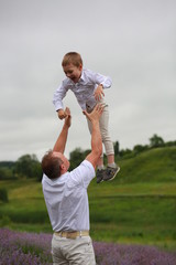  happy father rises to the sky  little son up, having fun and relaxing in a lavender field in summer