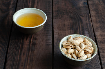 Almonds in nutshell and tea in cup on wooden background