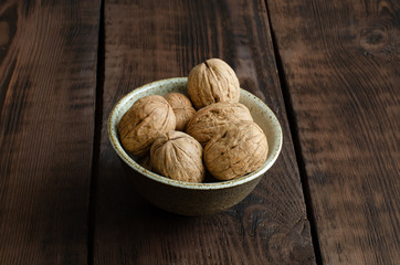 walnut with shell in bowl on wooden background.