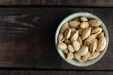 Almonds in bowl on wooden background. Top view.