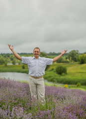  young man in a white shirt in a lavender field in summer enjoying his holidays
