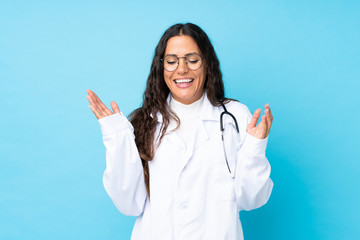 Young doctor woman over isolated blue background laughing