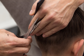 barber cuts the boy with scissors