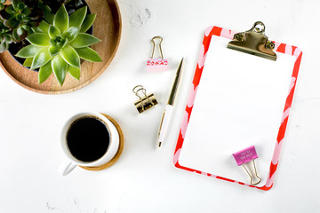 Flat lay fashion feminine home office workspace with succulent, cup of coffee, blank paper clipboard, pen and clips. Top view. copy space. Mockup concept