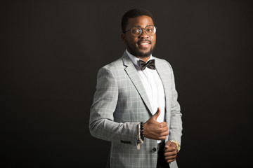 handsome young african man in suit on black background with hand gesture