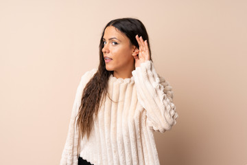 Fototapeta premium Young woman over isolated background listening to something by putting hand on the ear