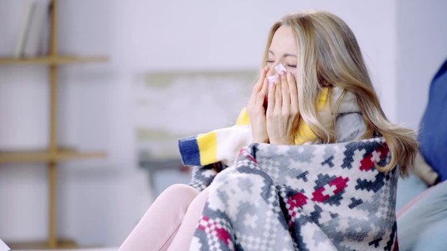 ill woman sneezing and using napkin