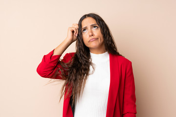 Young woman over isolated background having doubts and with confuse face expression