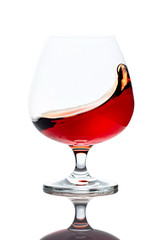 Splash of cognac in glass, isolated on white.