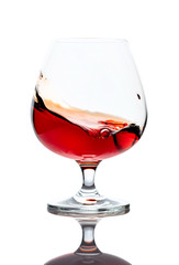 Splash of cognac in glass, isolated on white.
