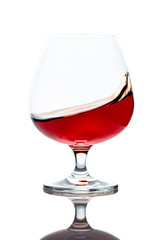 Splash of cognac in glass, isolated on white.