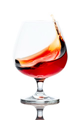 Splash of cognac in glass, isolated on white.
