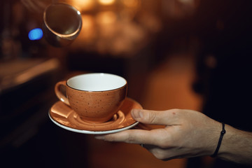 man holding an empty cup, male asking to pour tea or coffee, give me some coffee, please. close up cropped photo, blurred background