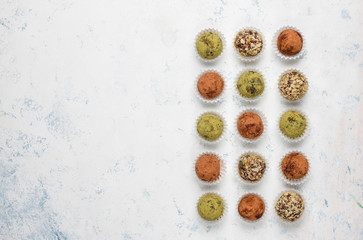 Homemade healthy vegan raw energy truffle balls with dates and walnuts,matcha powder,cocoa powder on light background