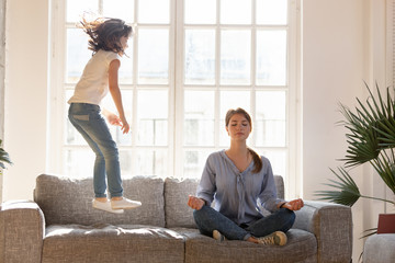 Mom meditating on couch ignore kid jumping near