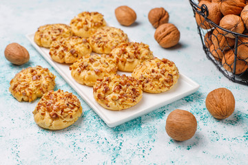 Homemade walnut cookies in white plate with walnuts on light background,top view