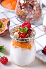Natural yogurt, granola and mashed passion fruit and mango layered in a glass jar. Breakfast idea