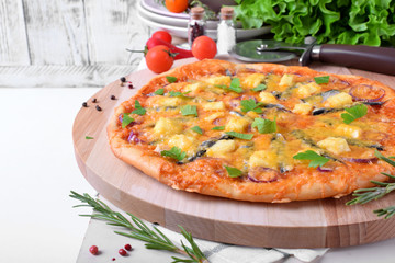 Round pizza with anchovies, mozzarella cheese and tomato sauce garnished with fresh parsley on white table