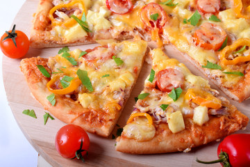 Pizza with chicken, cheese, tomatoes and bell peppers served on the round wooden board. Italian cuisine meal