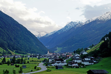 Fototapeta na wymiar Blick auf Neustift im Stubaital in Tirol, markante Kirche umgeben von Häusern und hohen Bergen, im Hintergrund der Stubaier Gletscher