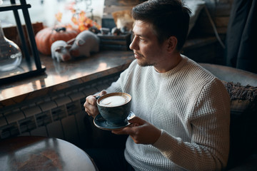 young pleasant guy having coffee break after work, enjoyment concept. close up side view photo. free time, lifestyle, leisure
