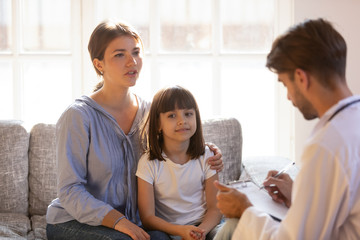 Male doctor visiting mom and daughter at home