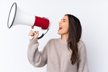 Young brunette woman over isolated white background shouting through a megaphone