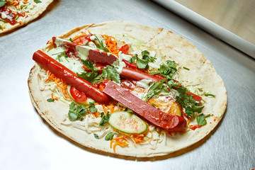 Open shawarma with smoked sausage vegetables, cabbage, herbs and white pita sauce on a metal surface. Tasty street food kebab