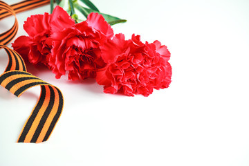 Three red carnations and St. George ribbon (Russian symbol) on a white uniform background. Greeting...
