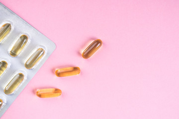 Oil yellow capsules on pink background