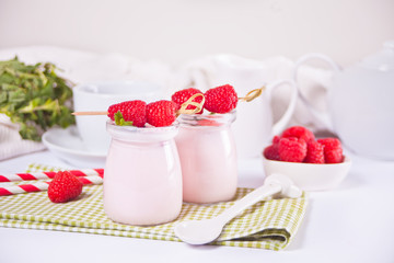 Two portions natural homemade yogurt in a glass jar with fresh raspberry. Breakfast concept.