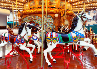 Fototapeta na wymiar white painted horses in a carousel decorated with lights and gold