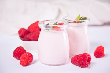 Two portions natural homemade yogurt in a glass jar with fresh raspberry. Breakfast concept.