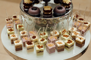 Delicious candy bar at luxury wedding reception. Exclusive expensive catering. Table with modern desserts, cupcakes, sweets. Space for text. Holiday celebration