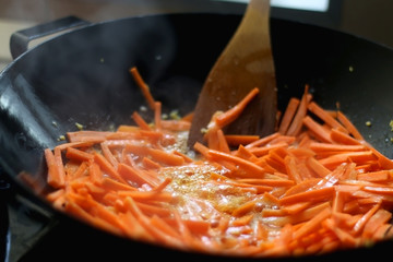 Stir fry carrot in a wok. Selective focus.