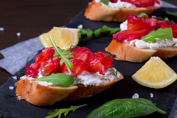 Trout Gravlax on the slices of white bread with ricotta topped with greenery on the stone platter. Nordic cuisine meal